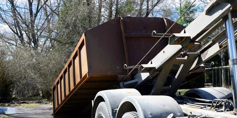 roll-off dumpster being unloaded from dumpster truck