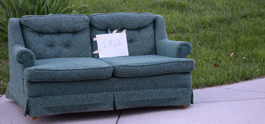 Old couch at the end of a driveway with a sign that says free