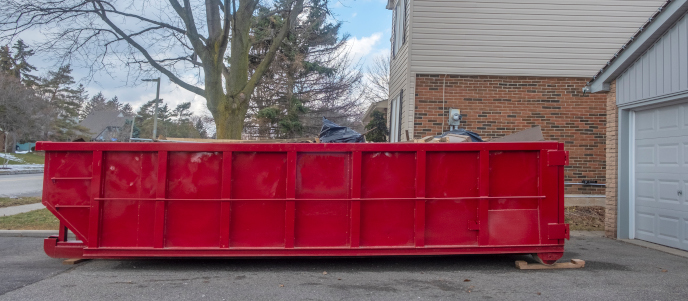Red dumpster placed on a residential driveway