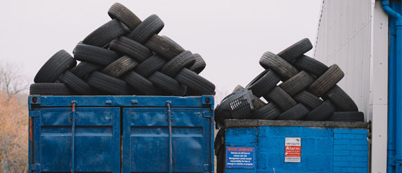car tires piled into a dumpster