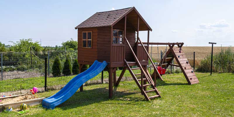 wooden swing set with slide in backyard 