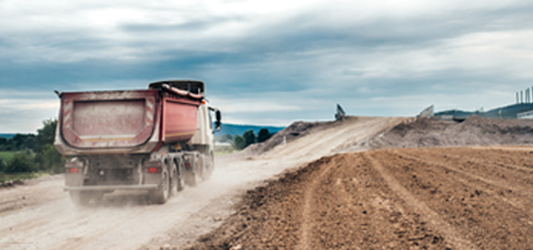 Roll-off dumpster on truck driving down dirt road